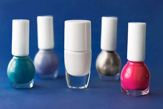 Nail polish bottles on dark blue background, beauty brand
