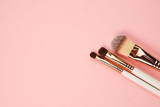 makeup brushes and eyeshadow professional cosmetics on pink background