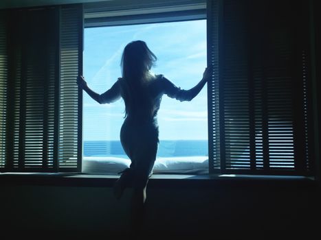 Woman looking outside the big window with sea view, luxury trave