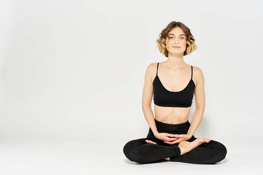 Woman in leggings meditate in a light room with her legs crossed yoga asana