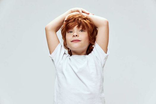 red-haired child holding hands on head white t-shirt cropped view
