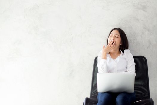 Portrait of beautiful asian young woman yawn at her work place w