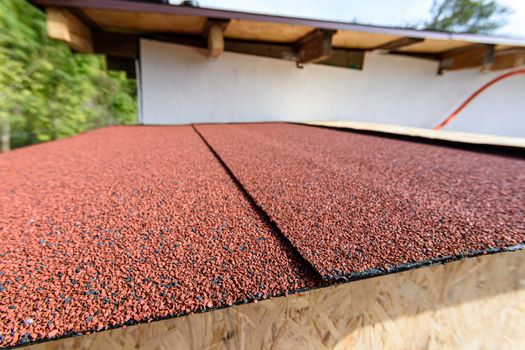 The roof of a small house is covered with a roof - soft bitumen roll tiles