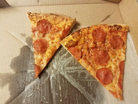 slices of pepperoni pizza with grease in box