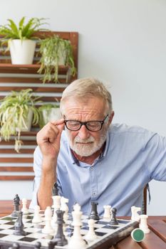 Senior retirement man playing chess with himself at home