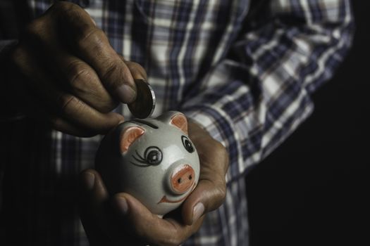 Saving money concept and hand putting money coin into piggy bank