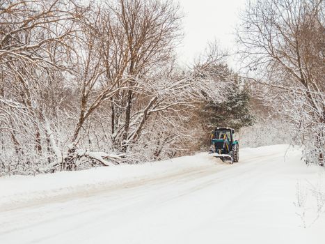 Snowplow clears rural road of snow debris after heavy snowstorm.