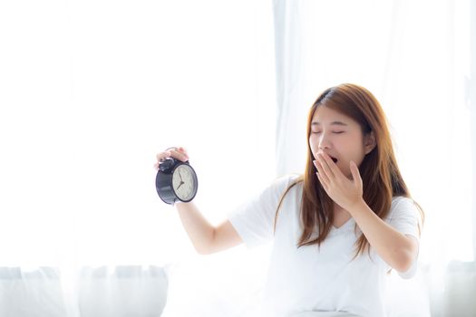 Beautiful young asian woman yawn wake up in morning annoyed alar
