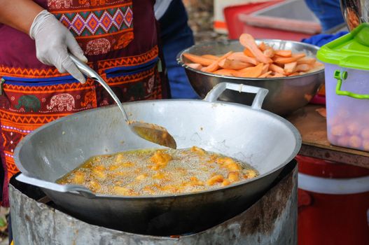 Sweet Potatoes being fried in Frying Pan with Heat Palm Oil, Fried Sweet Potatoes is Thailand Street Food or Thai Snack.