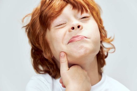 Red-haired boy grimaces hand face close-up