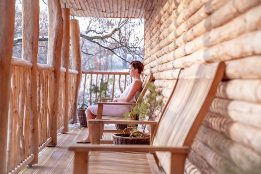 woman relaxes after sauna in a wooden log cabin in winter