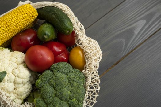 Bunch of mixed organic vegetables in reusable cotton mesh bag on a table. Zero waste concept. Eco friendly lifestyle concept. Groceries in eco bags. Plastic free items. Reuse, reduce, recycle, refuse.