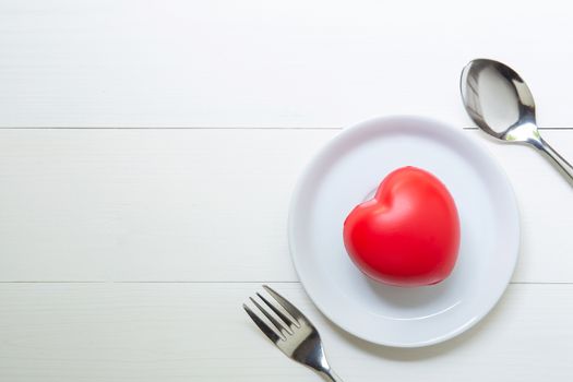 Red Heart with love and dish and spoon and fork on wooden backgr