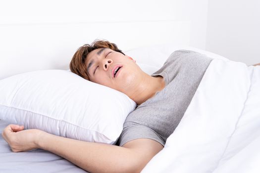 Man snoring loudly because of tired from work, sleep apnea lying in the bed. Healthcare medical or daily life concept.
