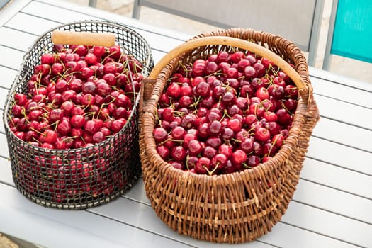 two baskets filled with beautiful red cherries on a garden table