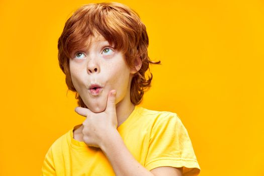 surprised red-haired boy looking up hand near chin