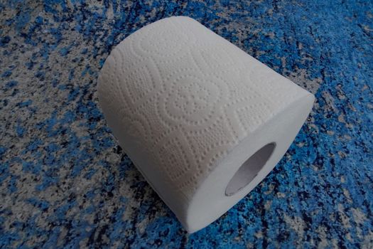 A roll of toilet paper on a blue background. Top view.