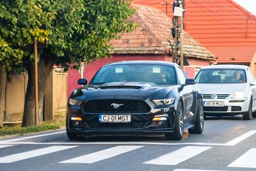 Traveling Ford Mustang car in motion on asphalt road, front view