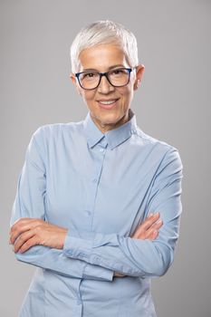 Senior businesswoman with glasses in a blue shirt and gray white
