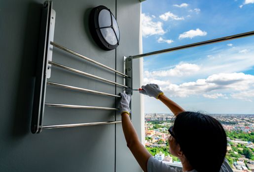 Asian woman use screwdriver screwing screw into the apartment wa