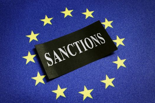 Europe Union EU flag and word sanctions on it.