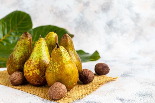 Pears on a light background. Autumn concept. Nearby are dried pear chips and nuts.