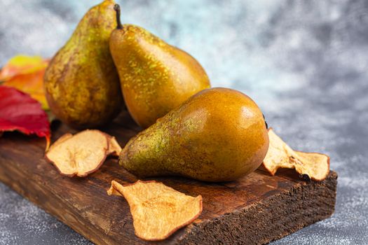 Pears on a light background. Autumn concept. Nearby are dried pear chips and nuts.