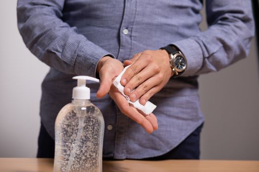 Man applying disinfectant alcohol gel on hands with wet wipes