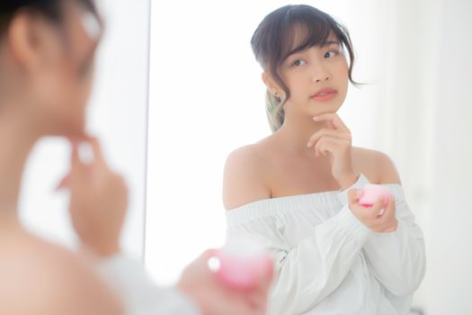 Beautiful portrait young asian woman applying cream moisturizer 