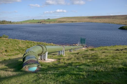 Very large shiny green metal pipe feeds into an extensive reservoir