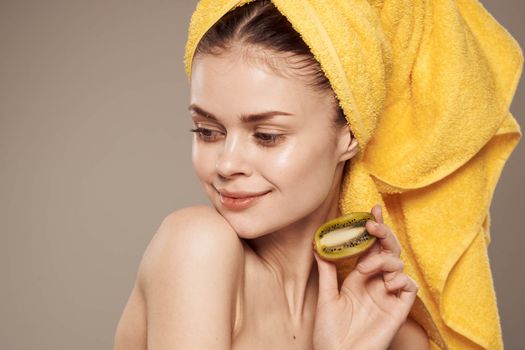 cheerful woman with a towel on her head and hands skin care naked shoulders beige background
