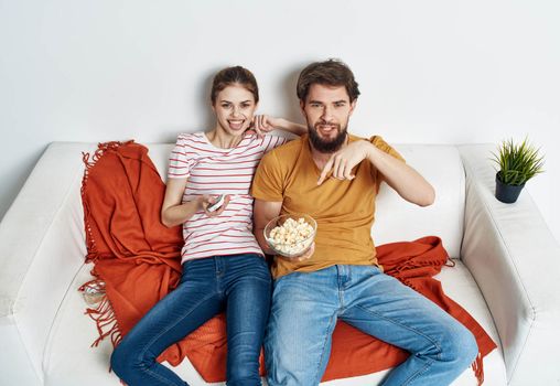 Couple in love with popcorn and watching TV while on the couch indoors