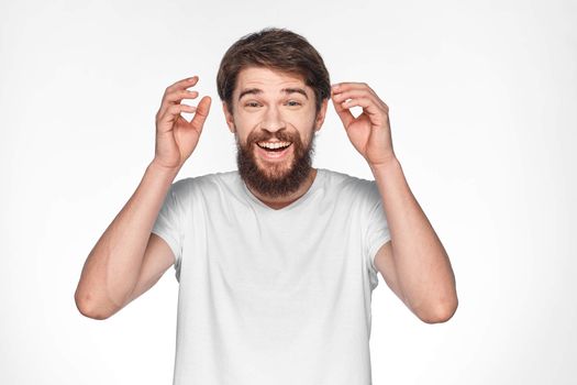 Bearded man in white t-shirt gesture with hands emotions light background
