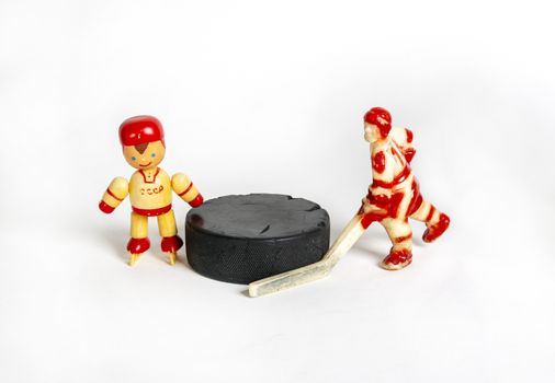 Hockey. Two red toy hockey players stand next to the puck