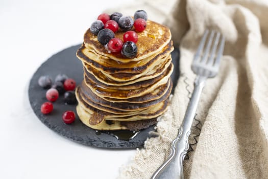 Plate with pancakes and berries on white table