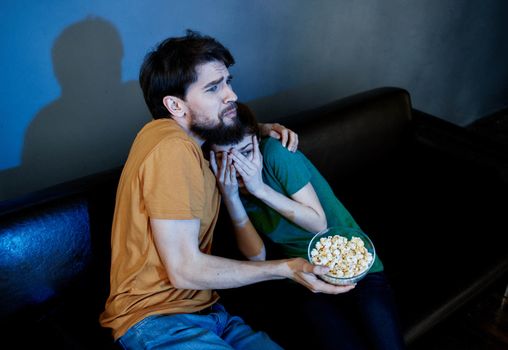 Men and women on the couch In a dark room watching a horror movie