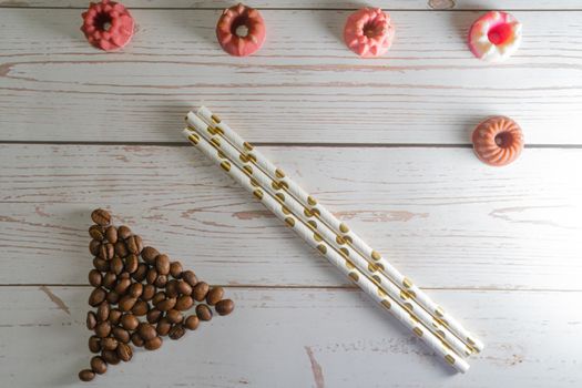 flatlay concept abstract showing coffee beans, straws, candies candles on a white wooden background perfect for a cafe menu or restaurant with copyspace