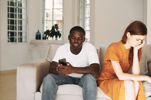 man and woman on sad facial expressions sitting on sofa conflict