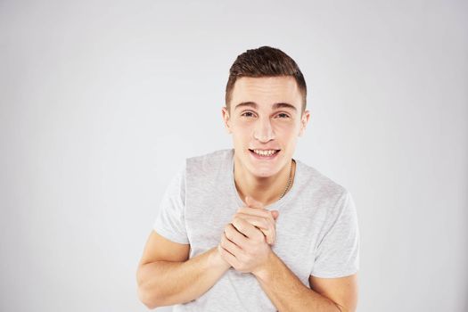 Man in a white t-shirt emotions gestures with hands close-up cropped view light background