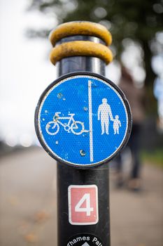 Blue sign on a pole indicating the pedestrians and cyclists paths