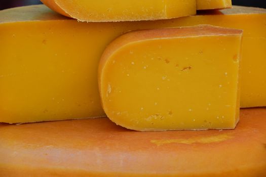 Close up cut slices and wheel of hard gouda cheese