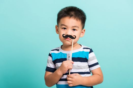 Funny happy hipster kid holding black mustache