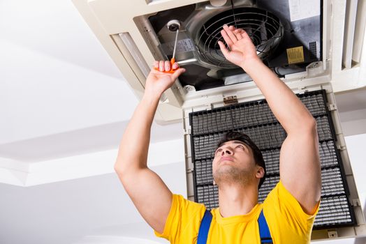 Repairman repairing ceiling air conditioning unit