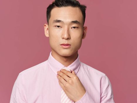 asian man adjusting tie self confidence close-up pink background model
