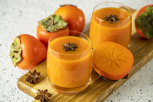 Two glasses of fresh healthy persimmon smoothie with anise stars