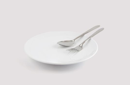 Dish spoon and fork isolated on white background, utensil for food, ceramic plate with empty, kitchenware or dishware with stainless in studio, object concept.