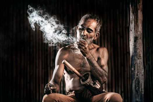 dark and sullen shot of a old man smoking over a black background