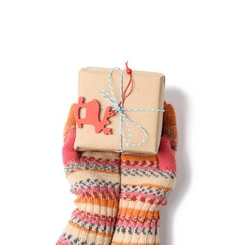 female hands in knitted mittens hold a box wrapped in brown paper and tied with a rope on a white background