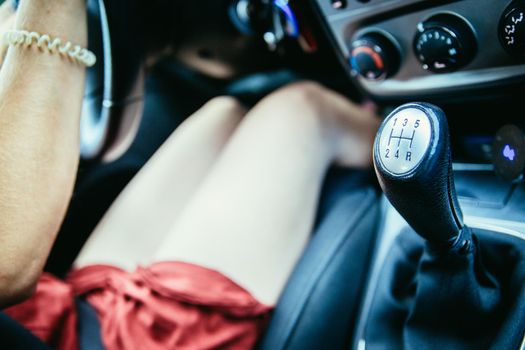 Young girl drives a car with manual transmission, shift lever