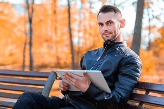 Youthful Guy Sitting on the Bench with Tablet PC
